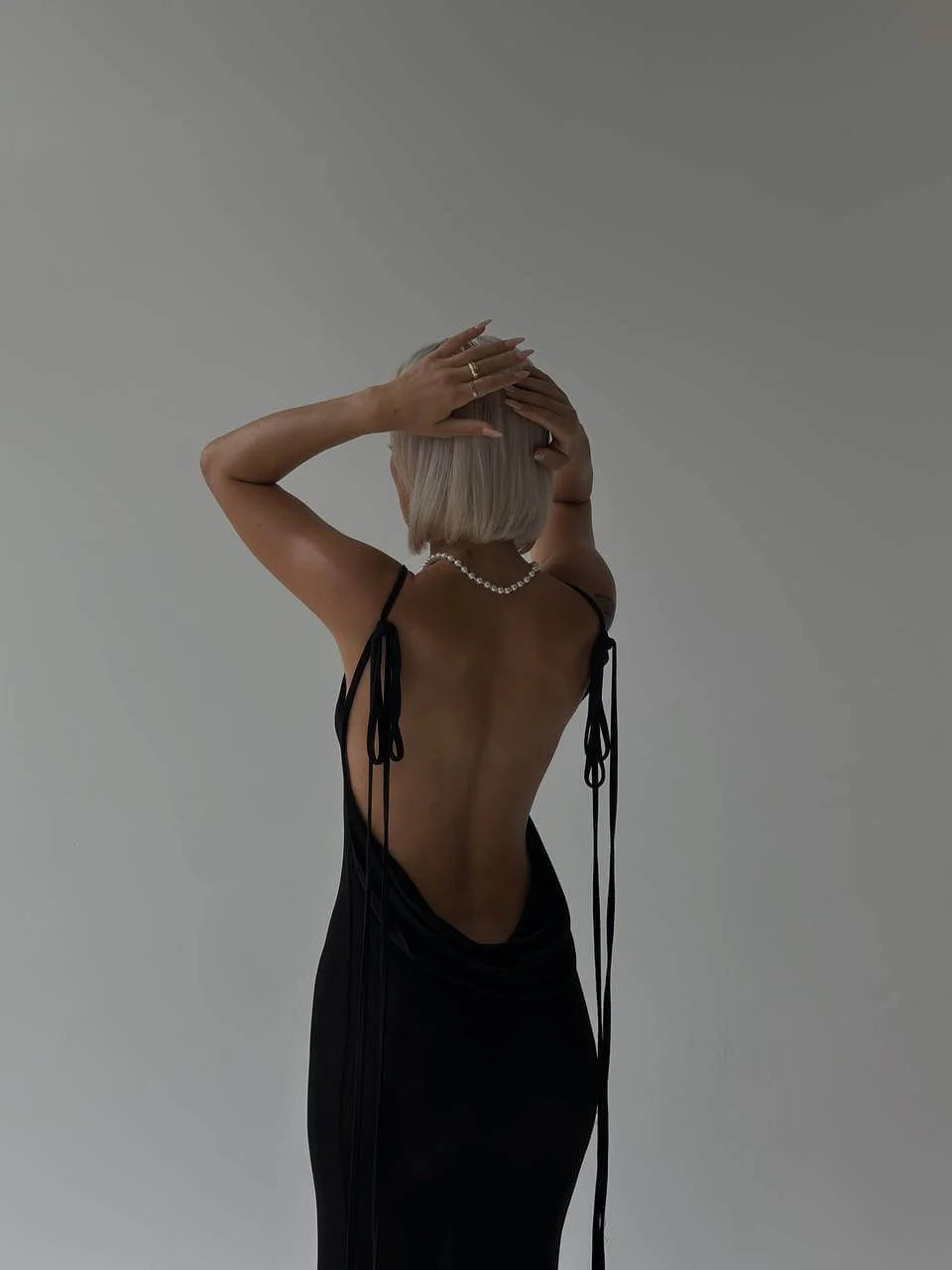 "Black backless top with adjustable ties, made from soft and stretchy fabric."