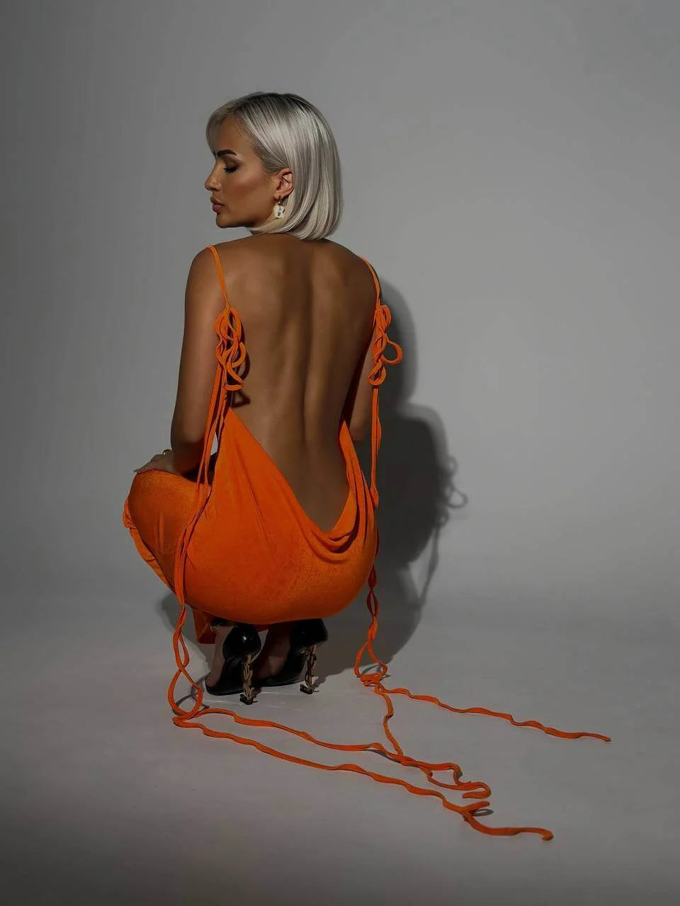 "Orange Aaira backless dress with adjustable ties, sleek modern design, perfect for casual outings or beach days."