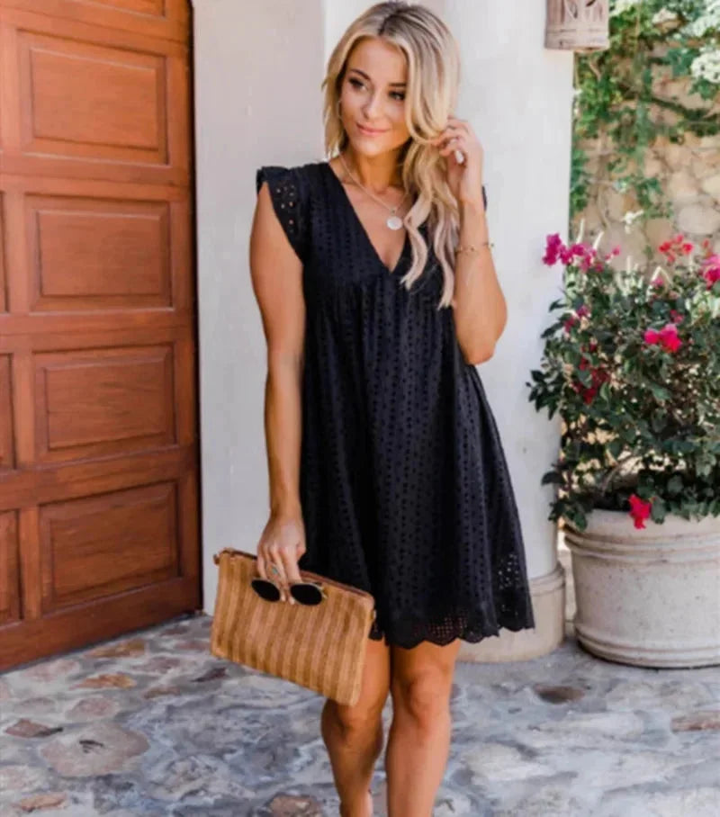 Black eyelet mini dress with V-neck and flowy design. Perfect for a fun and stylish summer look.