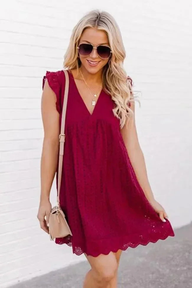 Burgundy eyelet mini dress with V-neck, flowy silhouette, perfect for day or night, made with intricate eyelet fabric.