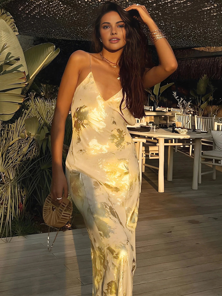 Gold foil satin maxi dress with straps, featuring a lustrous sheen and elegant design perfect for special occasions.