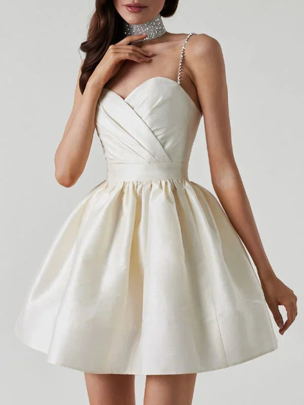 White mini dress with rhinestone straps, made of satin material. Elegant design perfect for special occasions.