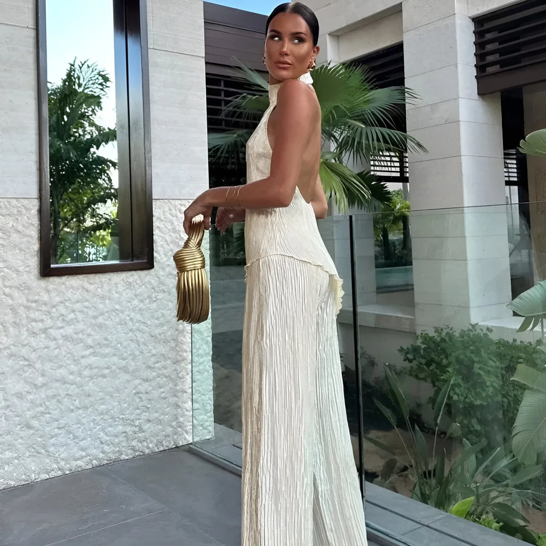 White pleated halter top jumpsuit in soft, flowing fabric with a flattering silhouette, ideal for effortless and stylish…