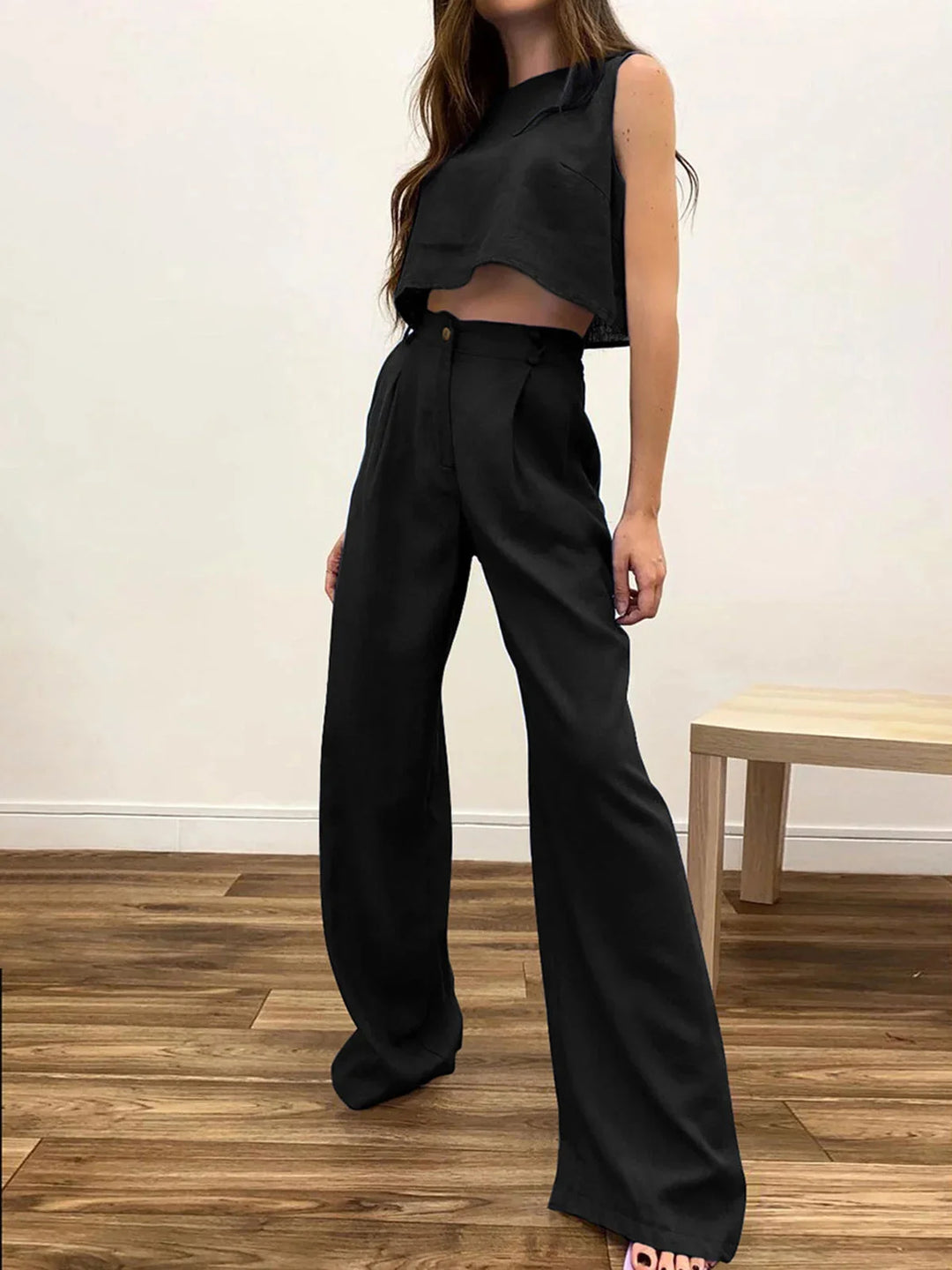 Black asymmetrical crop top and wide-leg pants set with a modern design. Made of high-quality fabric for a trendy look.