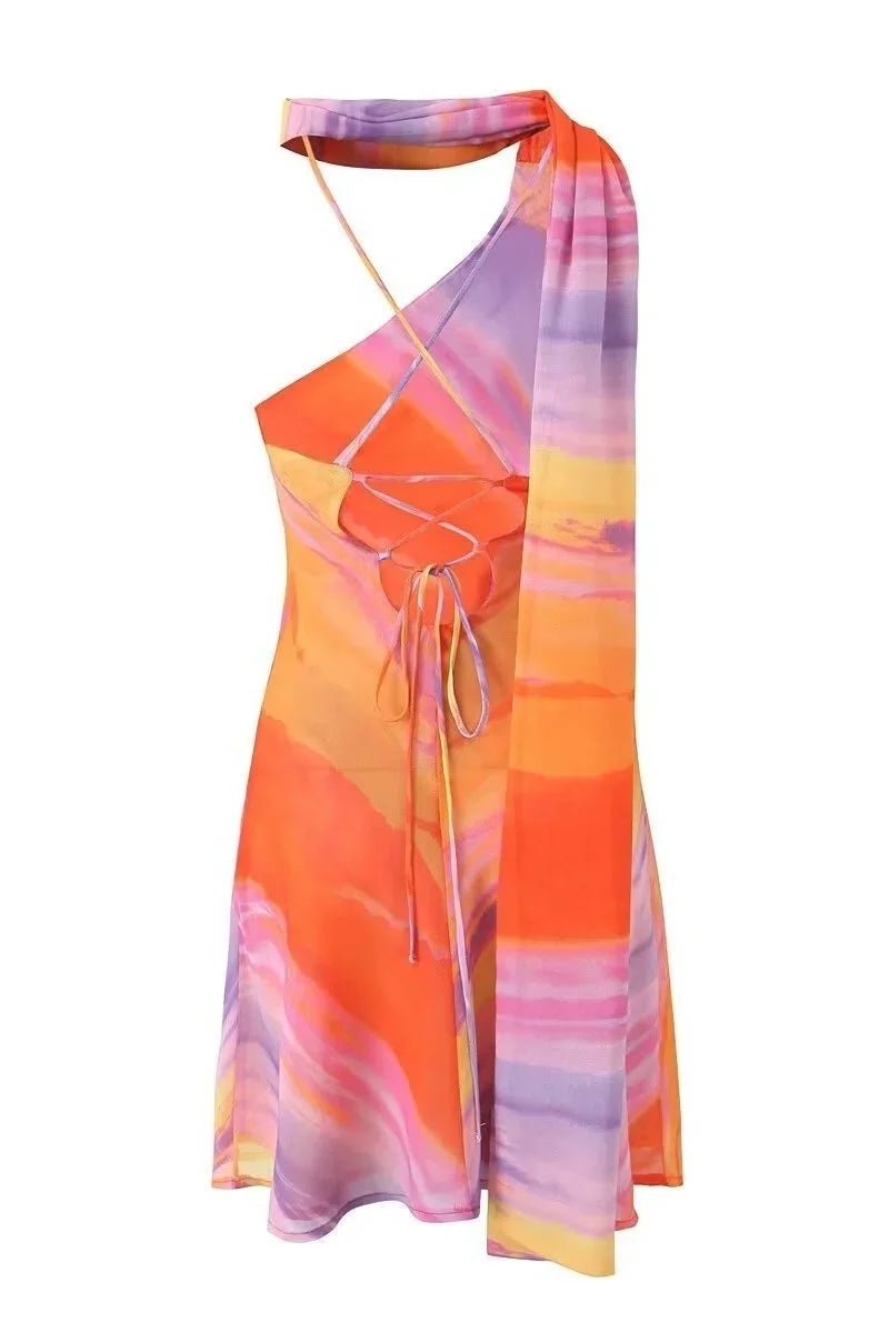 Aubrey Sunset tones halter mini dress featuring a vibrant pattern in warm colors with a halter neckline and mini length…