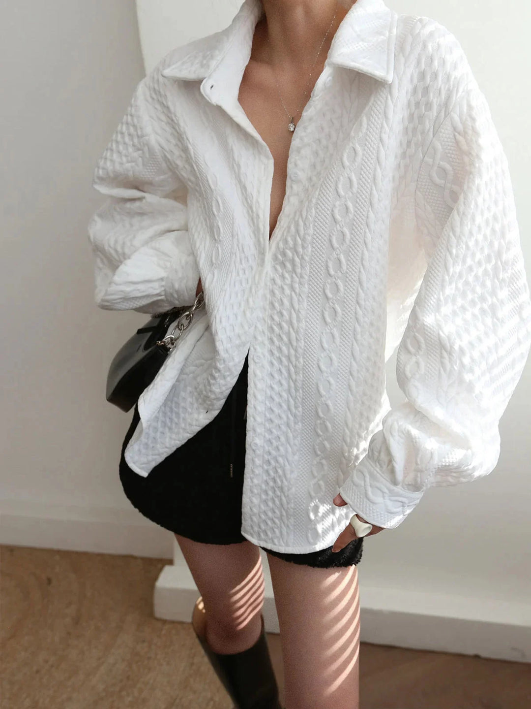White blouse with textured fabric and sculpted sleeves, perfect for a stylish and modern look.