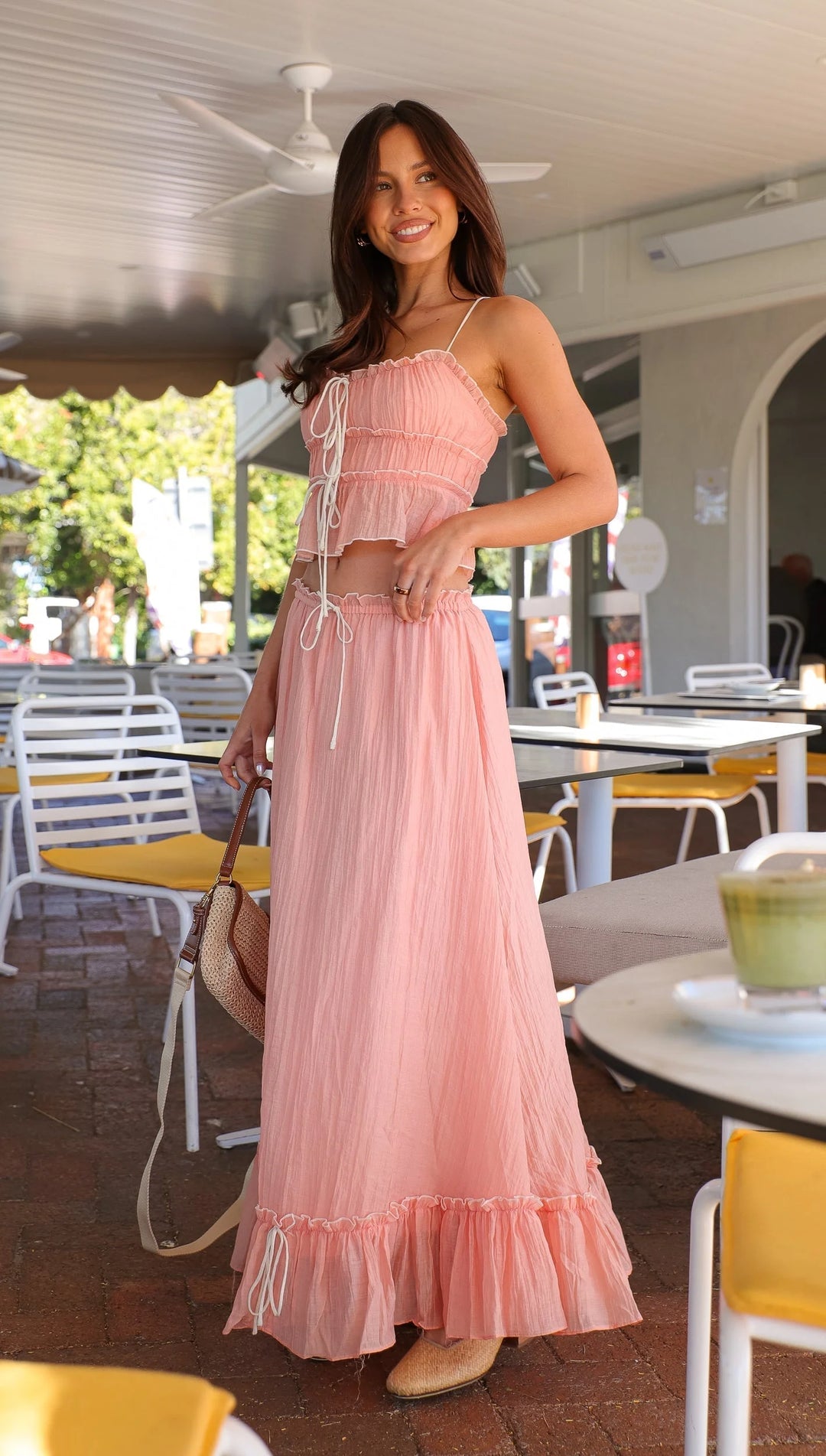 Pink ruffled maxi dress with ties, featuring a flowy design and a cinched waist. Perfect for a romantic summer look.
