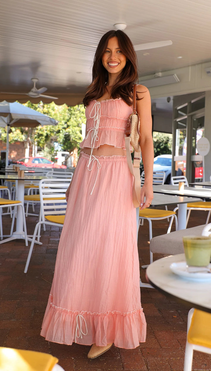 Alt text: Pink ruffled maxi dress with ties, featuring a flowy design, perfect for casual occasions.