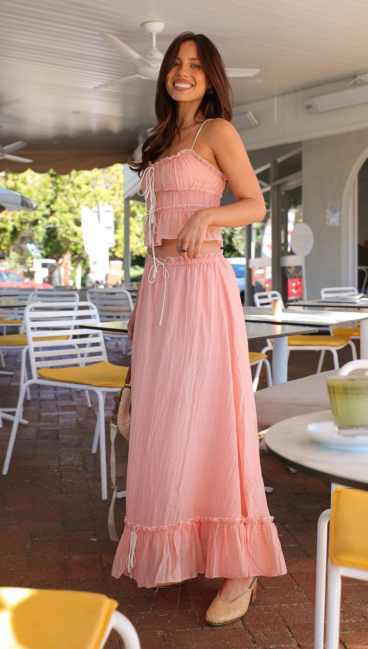 Pink ruffled maxi dress made of lightweight chiffon with tie details. Ideal for a chic and feminine look.