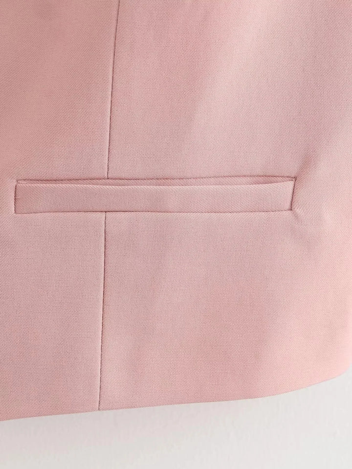 Soft pink V-neck vest with button details made from cozy, textured fabric perfect for casual chic outfit.