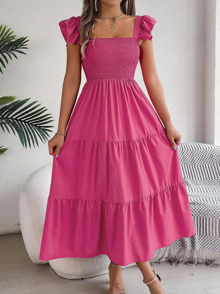 Pink tiered ruffle midi dress with smocked bodice. Soft, flowy fabric perfect for summer days or special occasions.