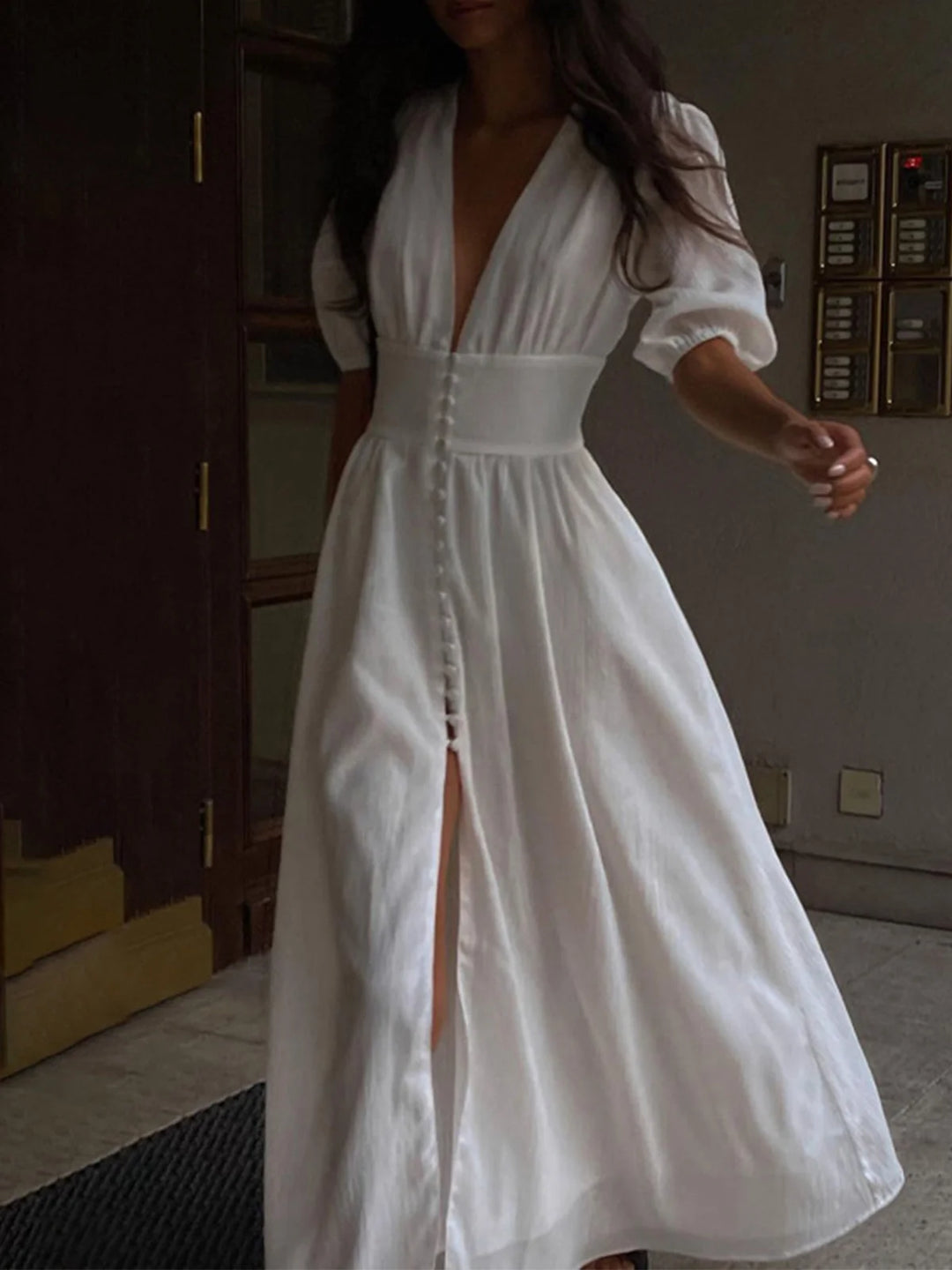 White shirt dress with fitted waist, front slit, and button detailing. Made from lightweight and breathable fabric for a…