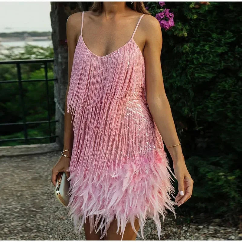 Pink spaghetti strap mini dress with sequins and feathers detailing. Perfect for a fun and flirty look for any special event.