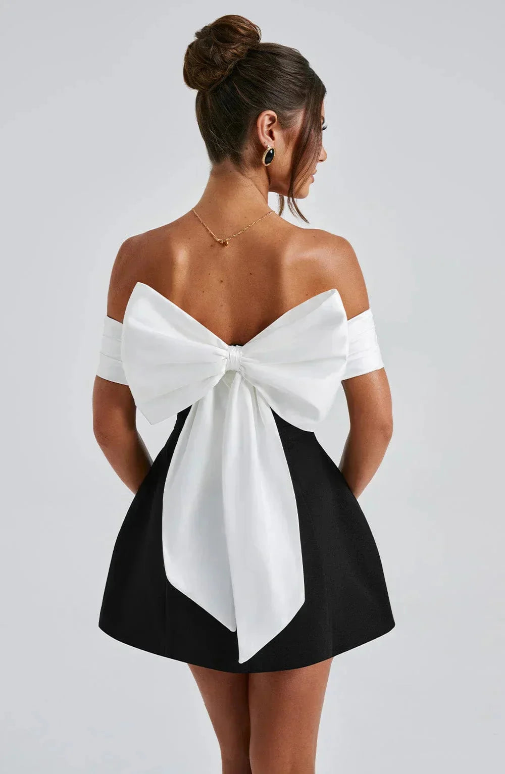 Off-shoulder mini dress in two-tone design with elegant bow detail, perfect for a chic and stylish look.