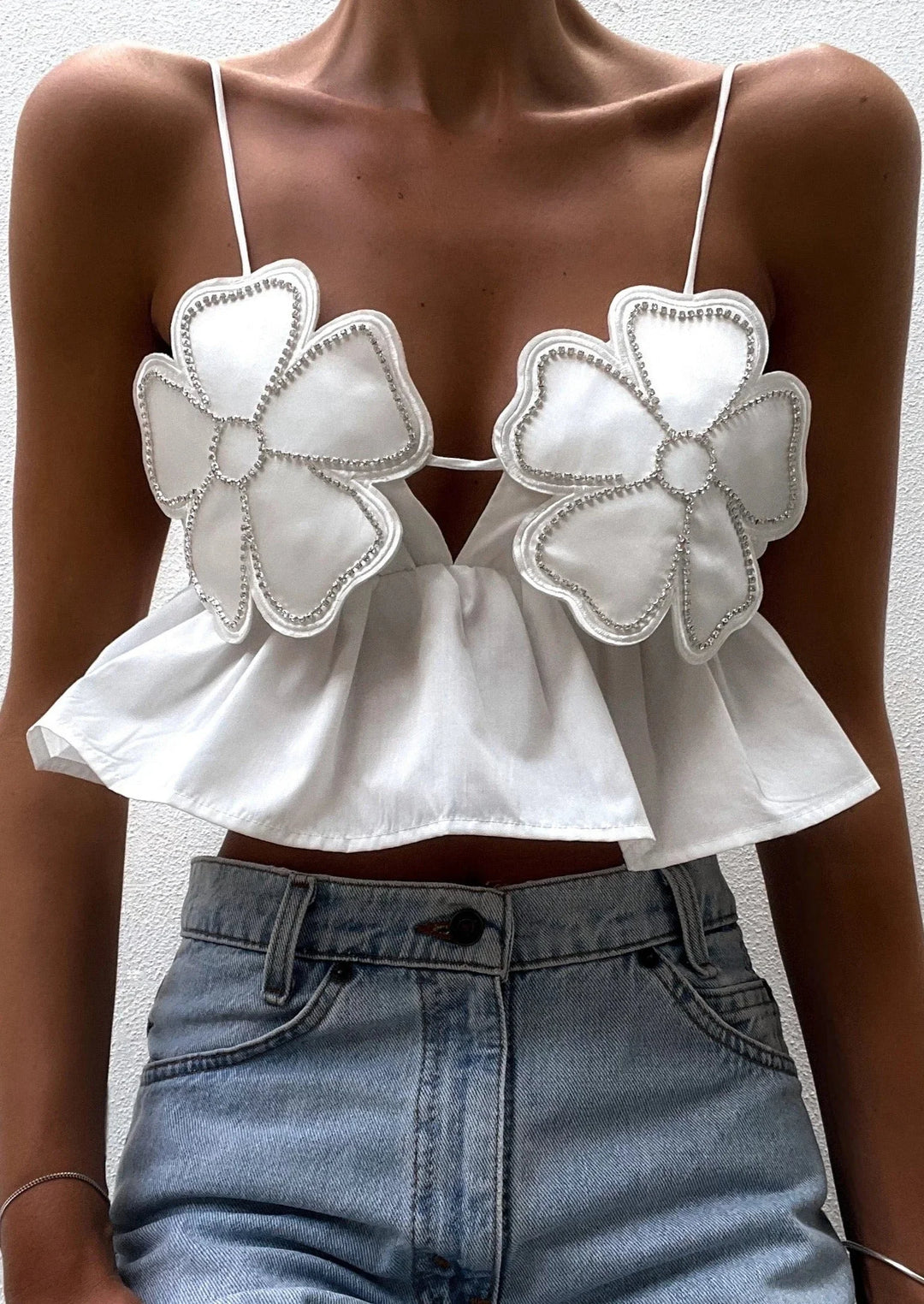 Floral applique crop top with a delicate design on a white fabric.