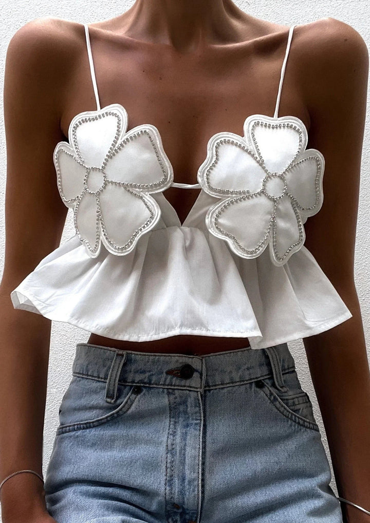 Floral applique crop top with a delicate design on a white fabric.