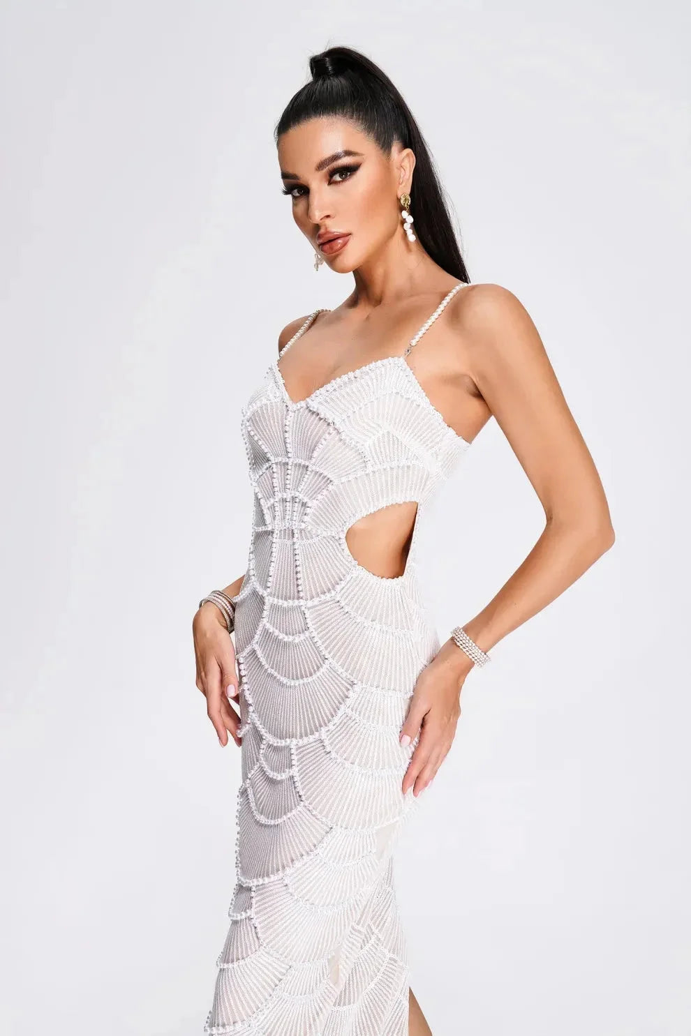 White sequined midi dress with thin straps on a mannequin. Perfect for special occasions with a glamorous and elegant design.