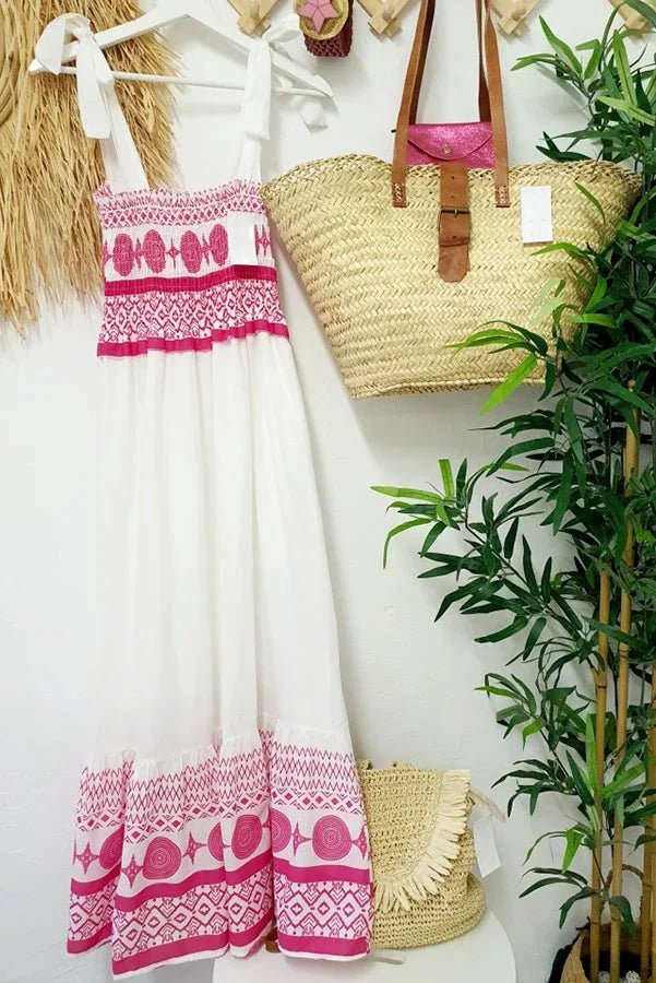 White maxi dress with pink tribal patterns, made of soft cotton blend. Perfect for a boho-chic summer look.