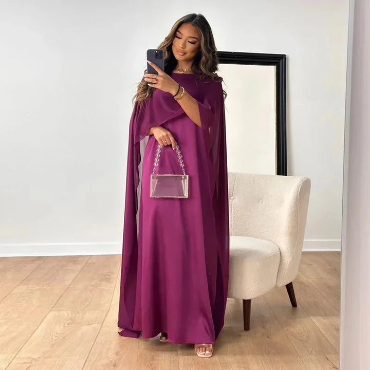 Purple cape maxi dress with intricate lace trim, perfect for evening events. Made from soft and flowing fabric for a…