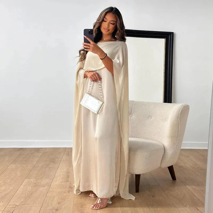 White cape maxi dress for evening wear, featuring elegant design with cape sleeves and flowing silhouette. Made from…