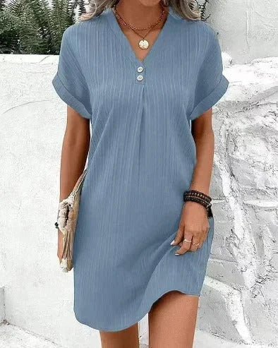 Light blue V-neck dress with pleats and buttons, made of soft and flowing fabric. Perfect for a casual and elegant look.