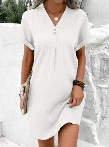 White V-neck short dress with pleats and buttons made of breathable cotton blend fabric. Casual yet chic summer style.