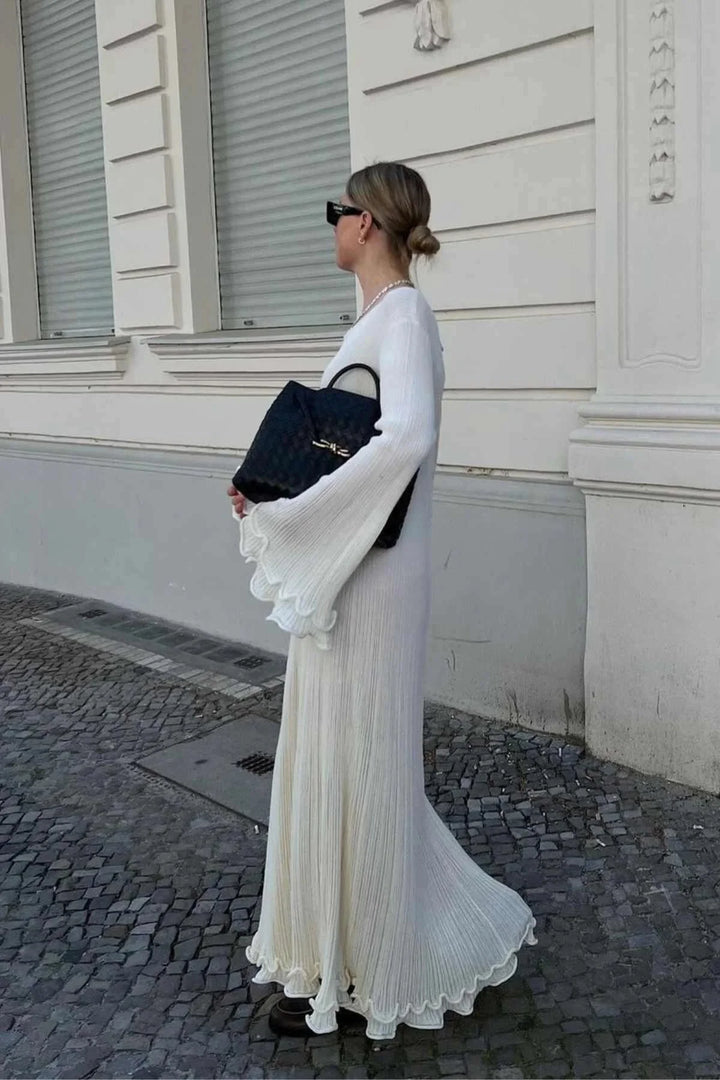 "White floor-length dress with bell sleeves, made from pleated fabric, elegant and timeless design."