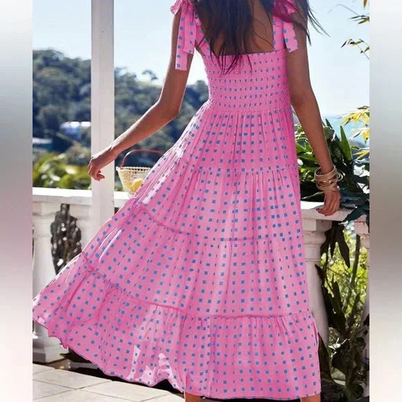 Pink smocked maxi dress with tie straps, made from lightweight fabric with a chic smocked design and adjustable tie straps.