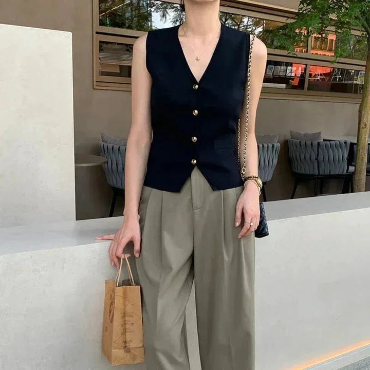 "Black sleeveless vest with button details, perfect for layering. Tailored fit with a stylish and contemporary design."