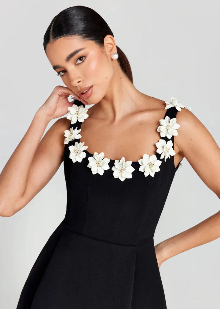 Black mini dress with white floral embroidery on bodice, made of soft and textured fabric. Perfect for a classy look at any…