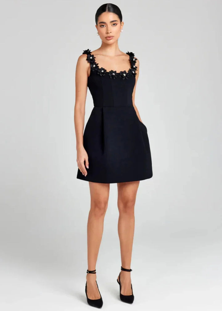 Black mini dress adorned with white floral embroidery, perfect for a chic and trendy look.