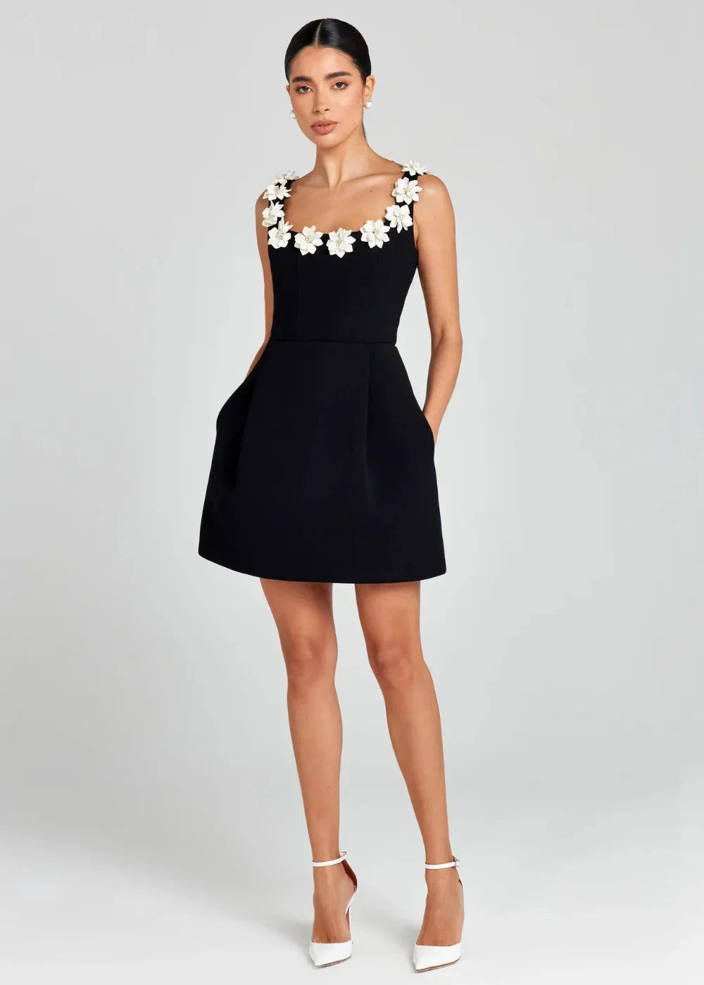 "Black mini dress with white floral embroidery, featuring a delicate and chic design for a stylish look."