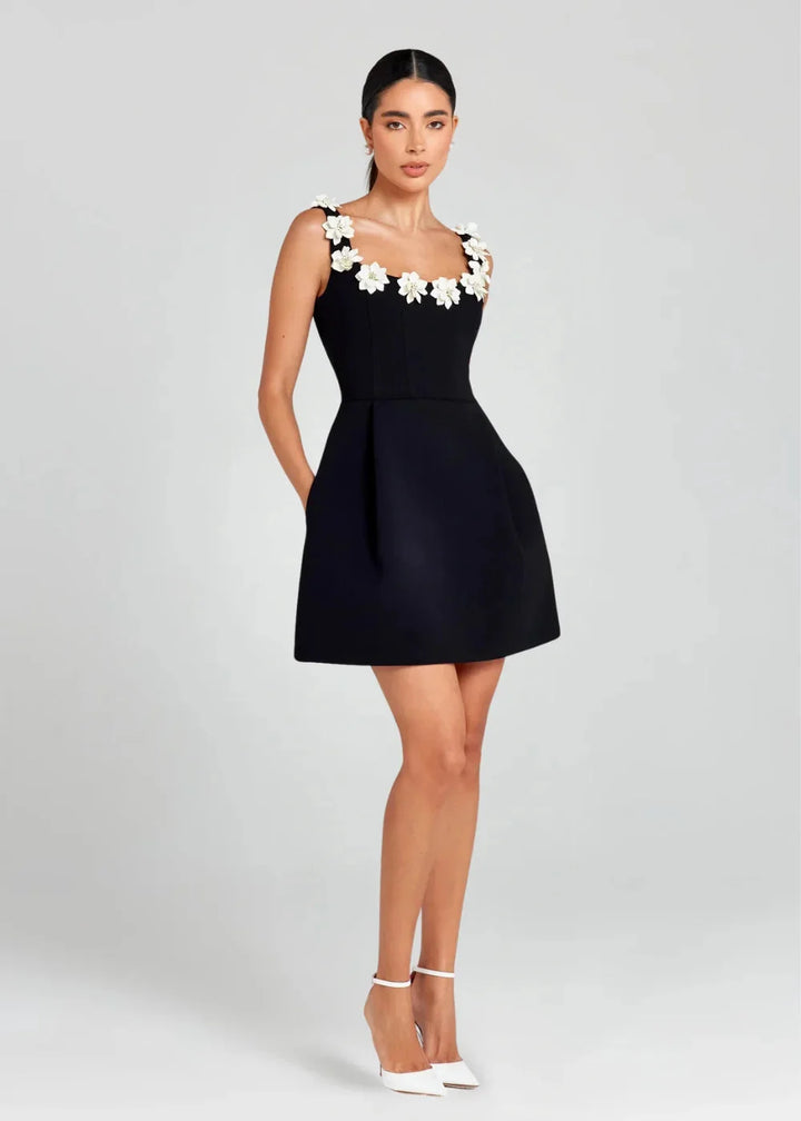 "Black mini dress featuring white floral embroidery, perfect for a chic and stylish look."