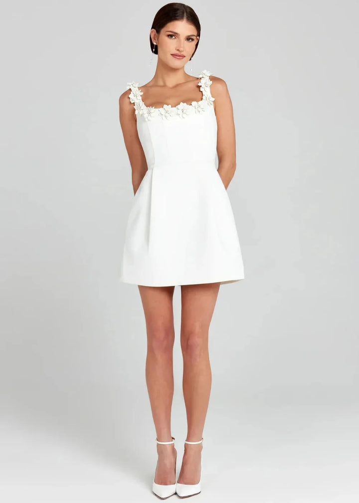 Black mini dress detailed with white floral embroidery on a lightweight fabric.