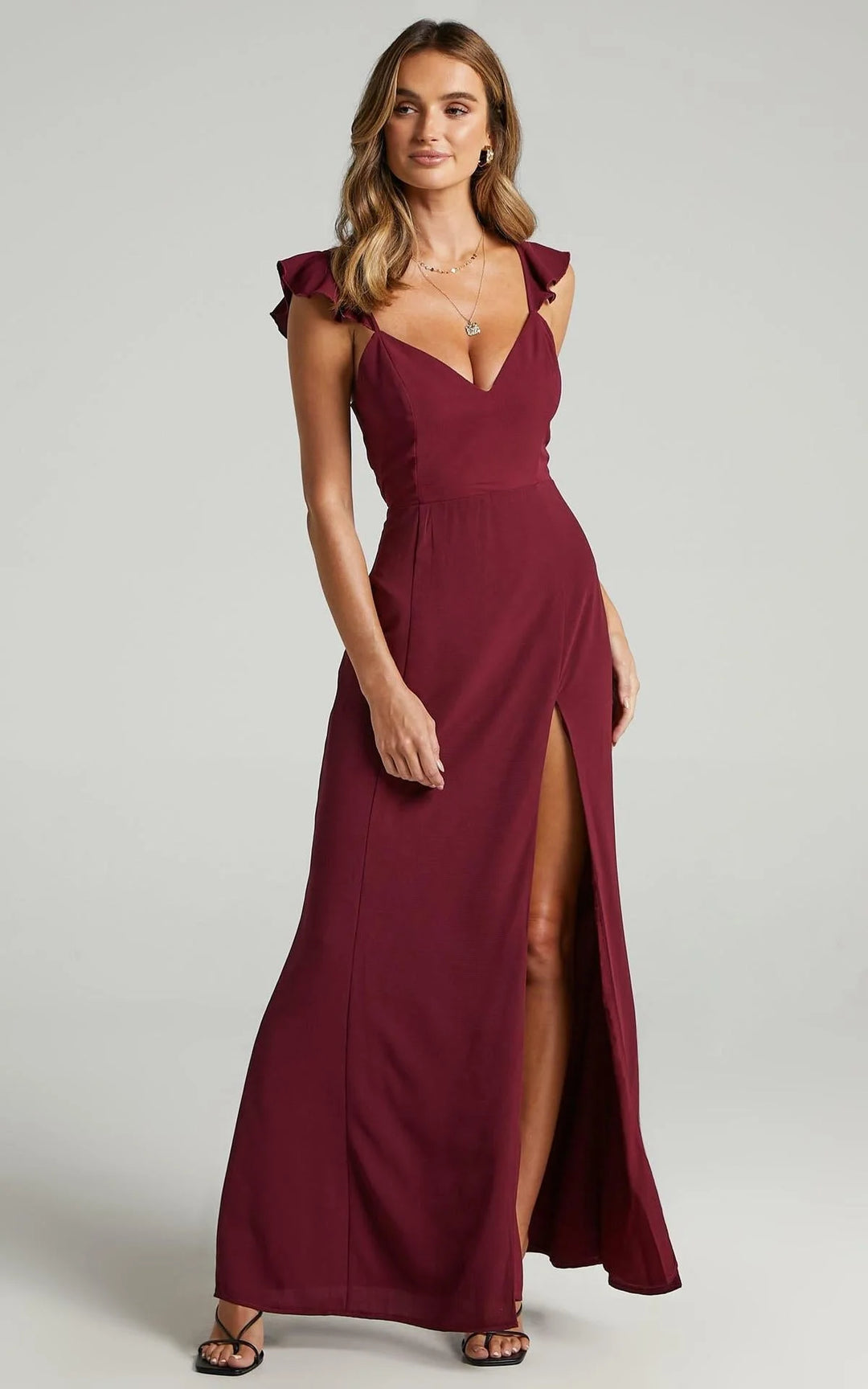 "Burgundy maxi dress with thigh split and sleeve details, made of flowy fabric with intricate stitching."