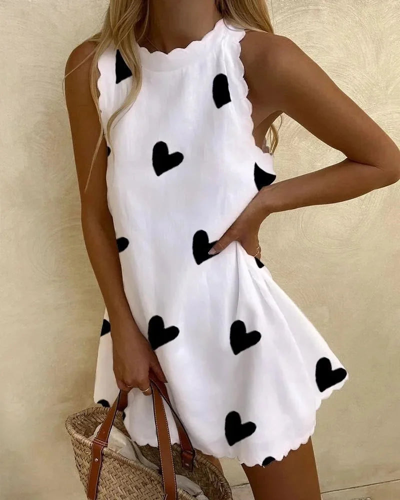 Black mini dress with heart print, ruffles, and a flowy silhouette. Feminine and chic, perfect for day or night wear.
