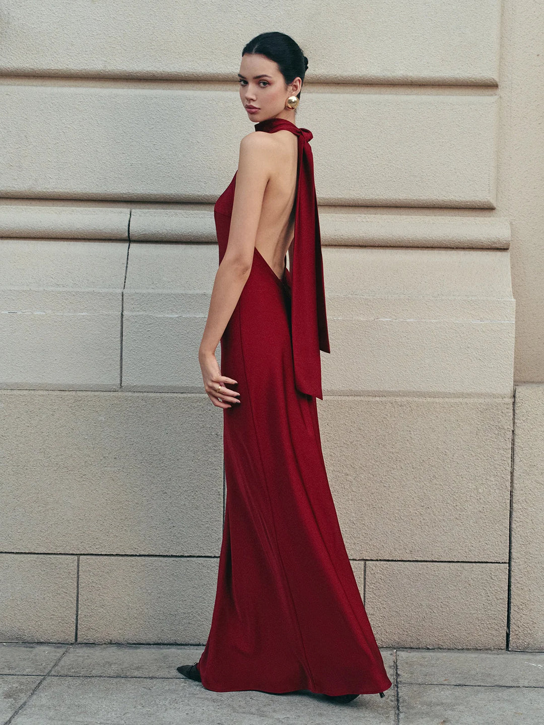 "Red satin halter dress featuring a trailing bow, perfect for formal occasions."