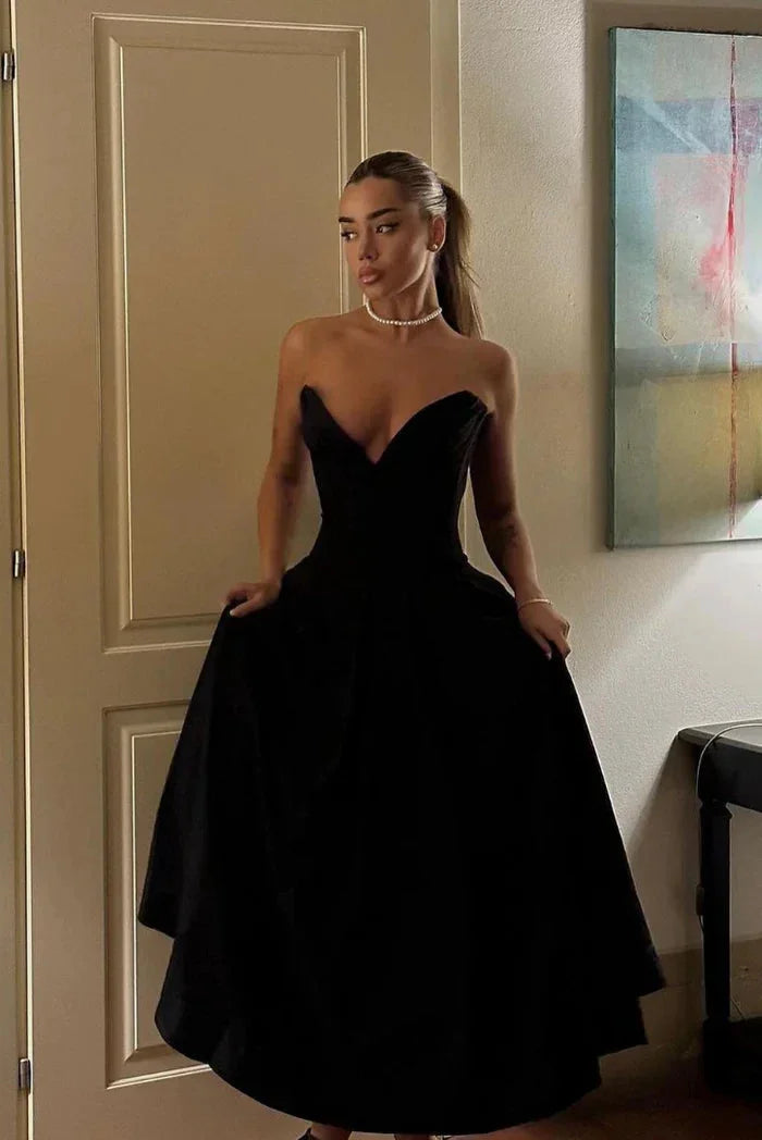"Kirra strapless corseted A-line midi dress in sleek black satin fabric with sweetheart neckline and elegant silhouette."