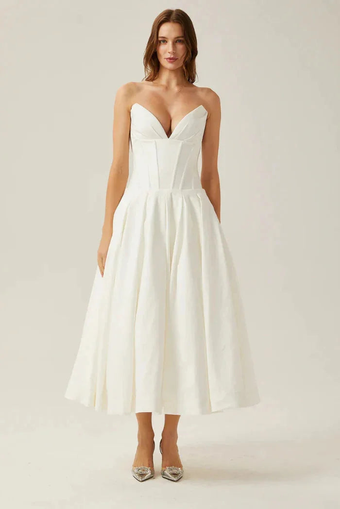 Strapless corseted midi dress in Ivory, A-line silhouette. Textured fabric with elegant gathers and boning detail on the…