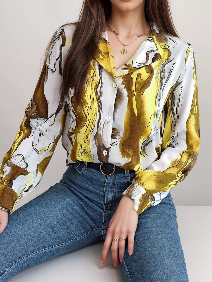 Yellow satin top with button-up front. Features an artistic design.