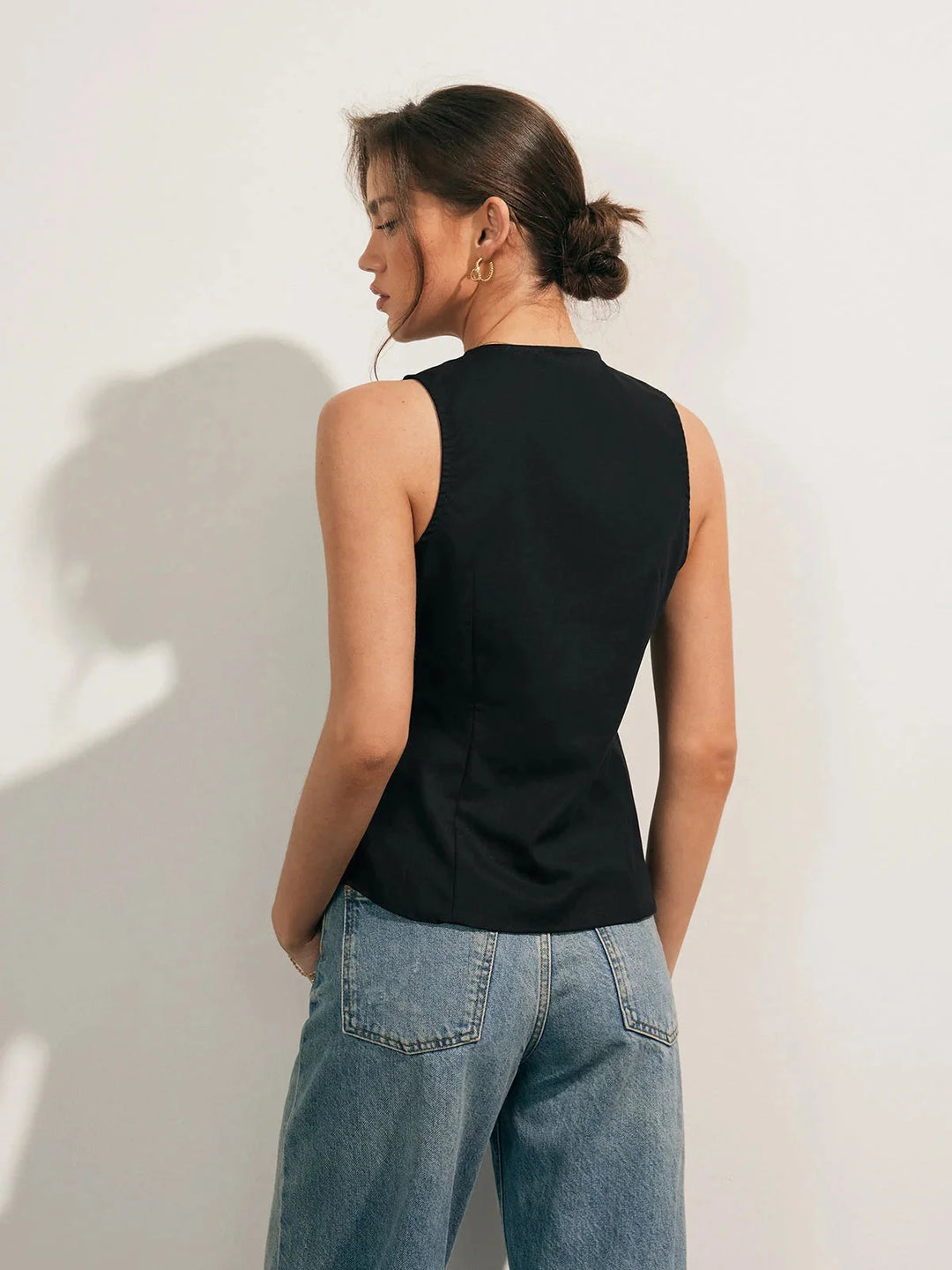 Sleek black sleeveless button-up collared shirt with a modern design, perfect for versatile styling with a sophisticated…