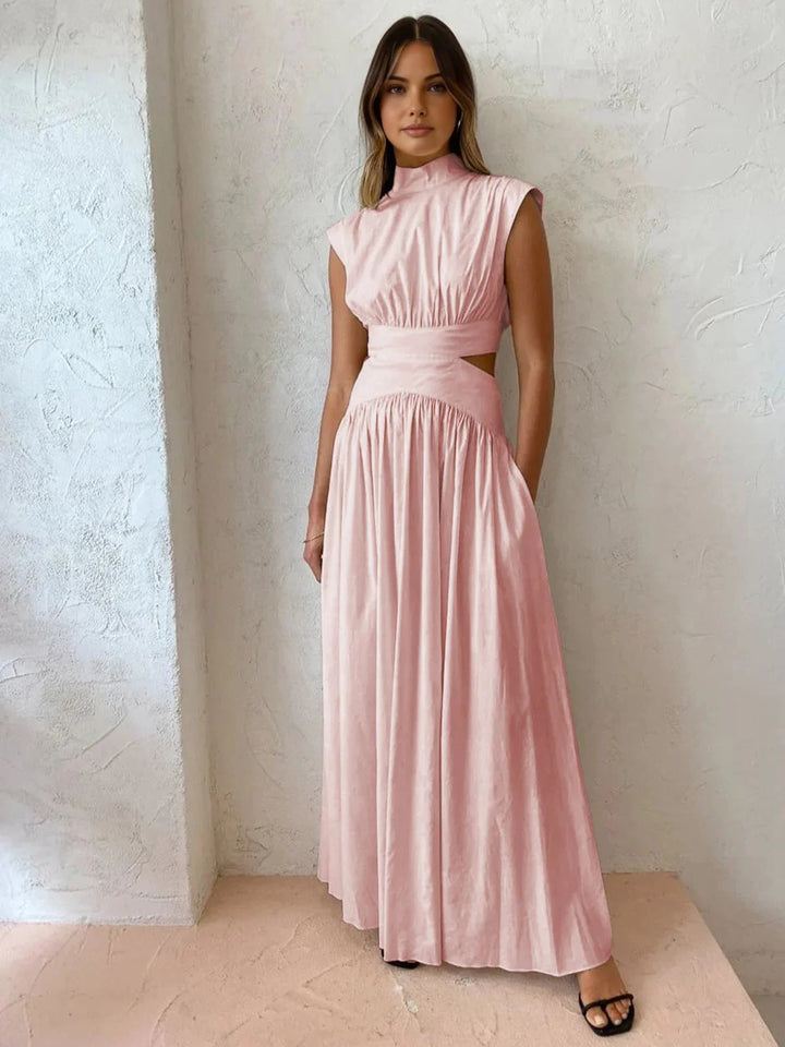 Pink sleeveless mock neck dress with cutouts. Features a flattering silhouette and stylish design. Perfect for a summer day…