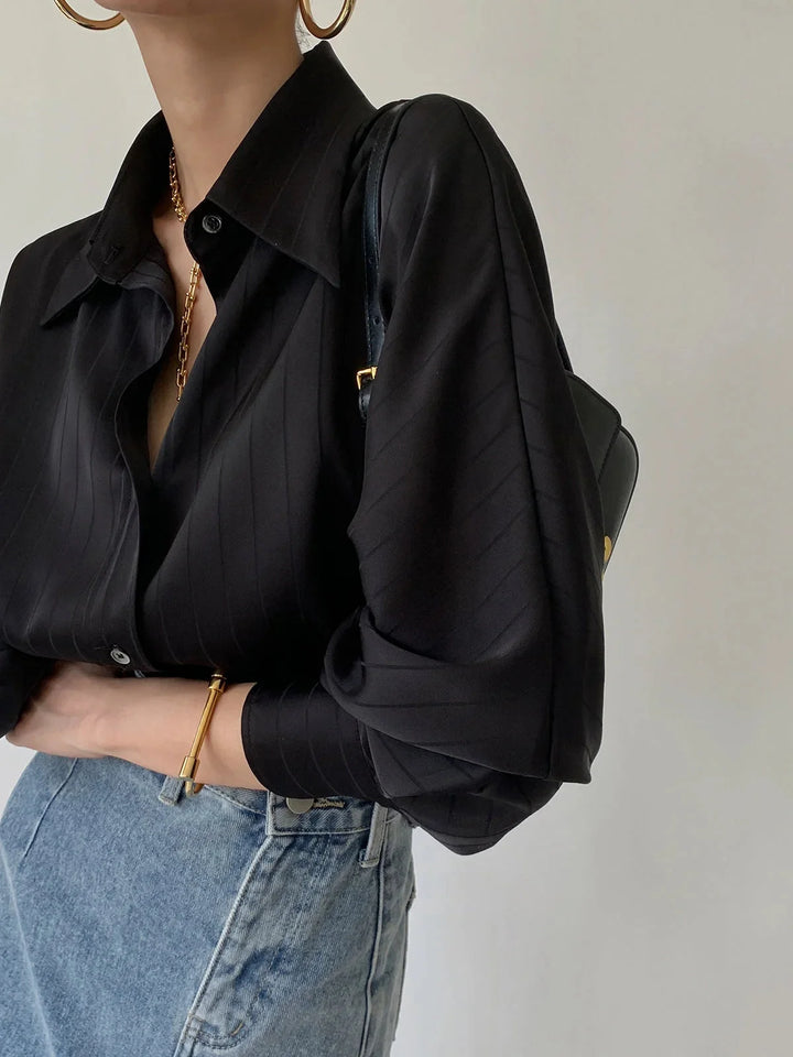 "Laylani black button-up shirt with elegant gold accents, made of sleek material, perfect for a sophisticated look."
