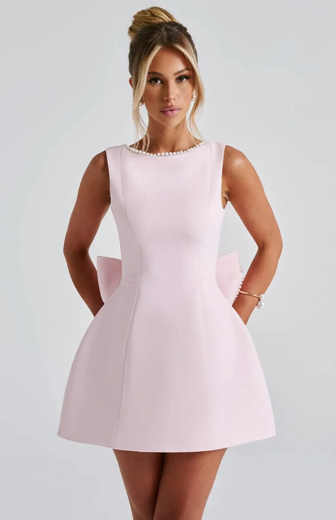 Sleeveless backless dress in black with white pearl detailing on spaghetti straps and a flowy chiffon skirt.