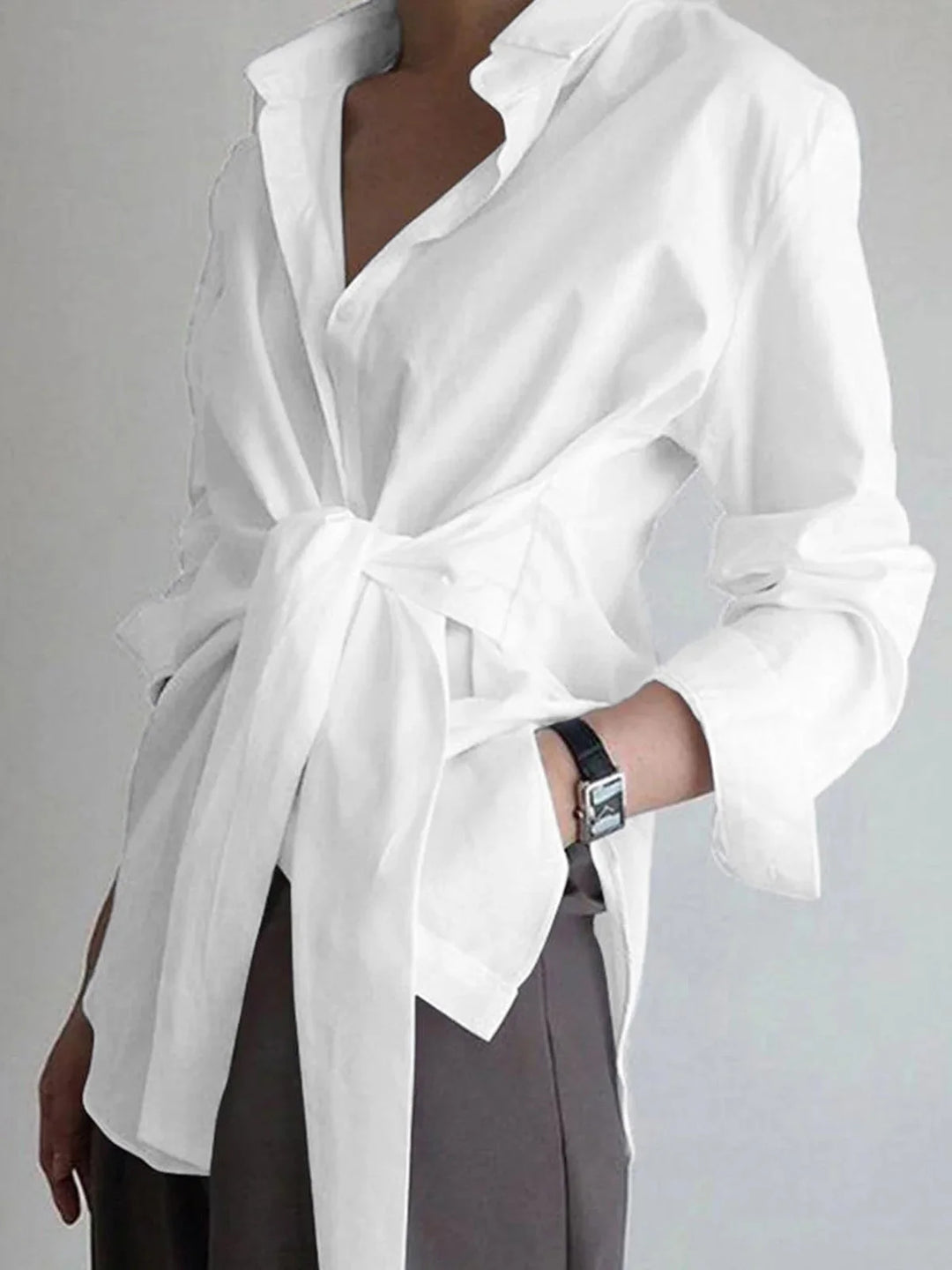 White adjustable front-tie blouse with buttoned cuffs made of soft cotton blend fabric. Classic and versatile design…
