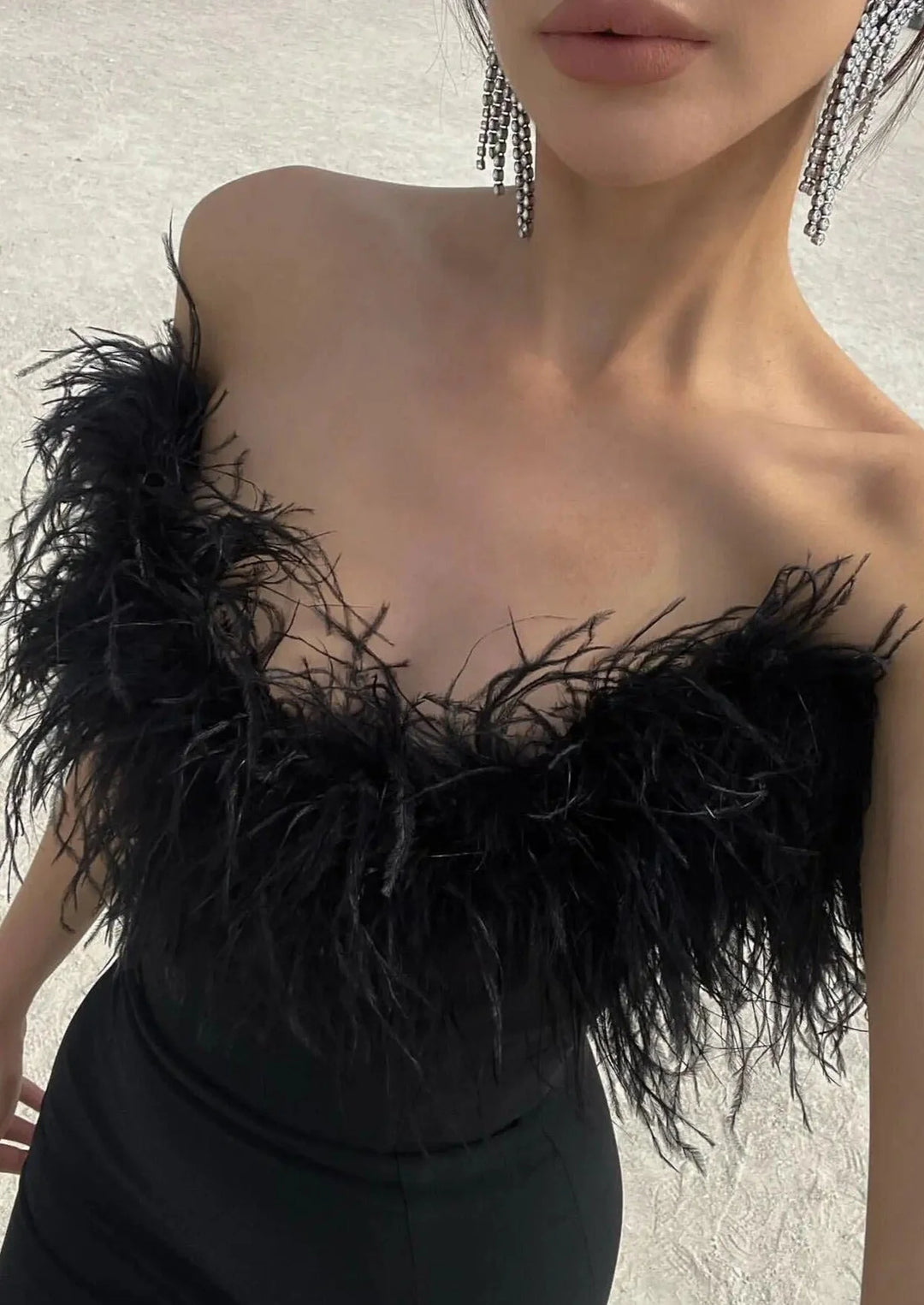 Strapless black dress with feather trim, perfect for special occasions.