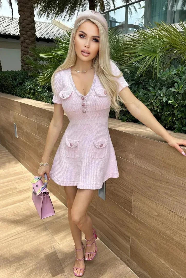 Pink short dress featuring side buttons and pockets made from breathable cotton blend fabric.