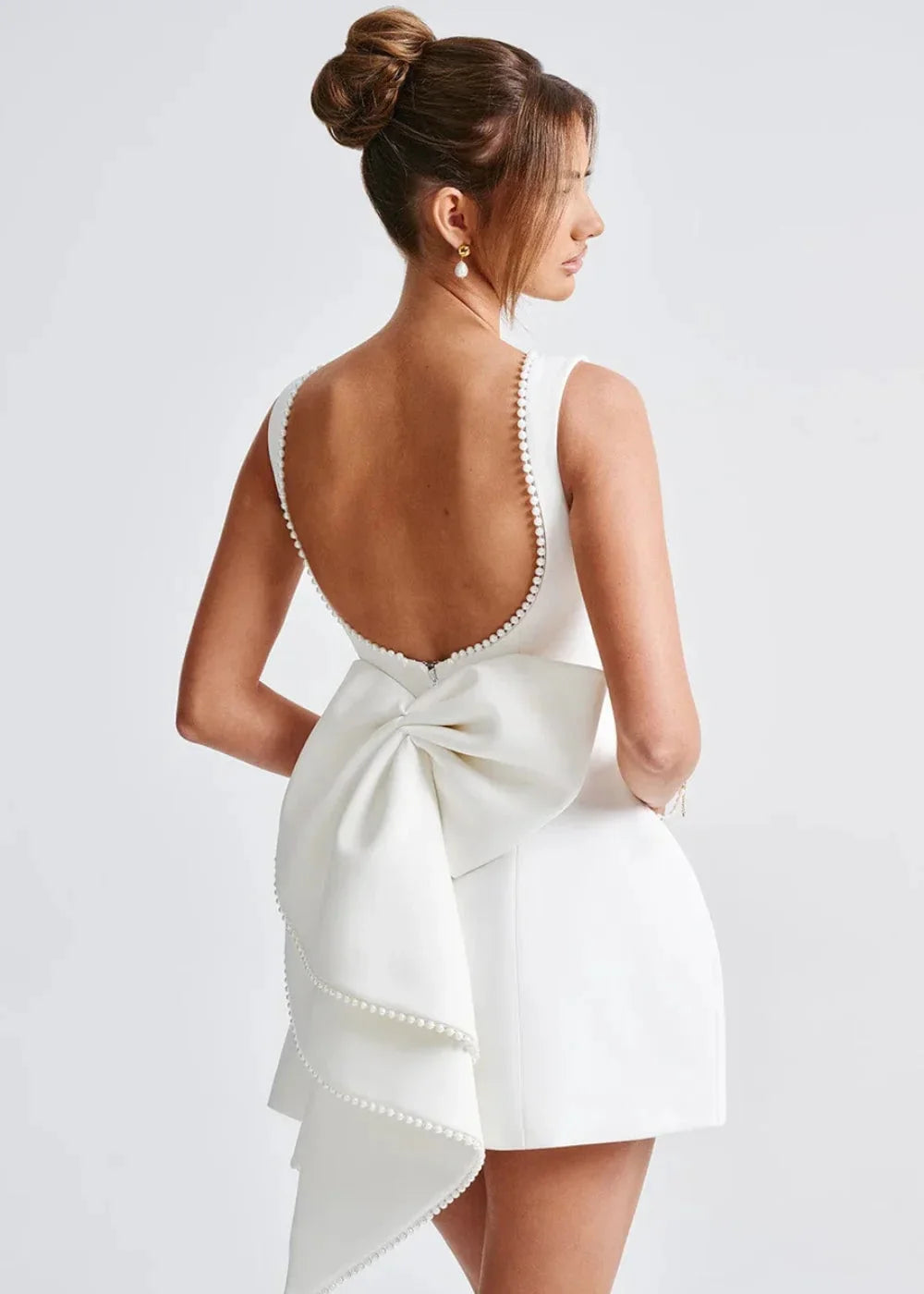 Black backless fitted mini dress with a bow detail at the back, crafted from a soft and stretchy fabric for a comfortable…