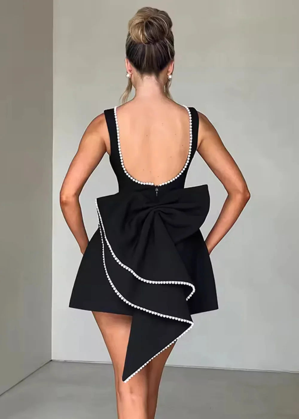 Black backless fitted mini dress with front bow detail. Made of soft and stretchy fabric for a comfortable and stylish look.