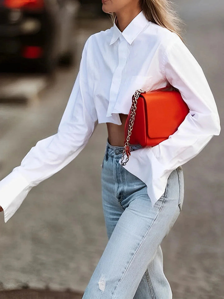 "Button-up cropped shirt in modern design with long sleeves and collar, made from soft cotton blend fabric."